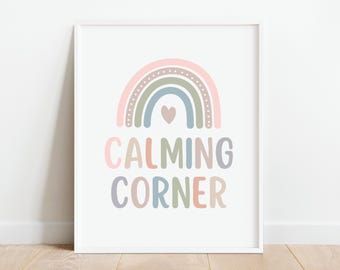 Puede incluir: Una impresión enmarcada en blanco con un arcoíris pastel y el texto "CALMING CORNER" en un arcoíris de colores. El arcoíris tiene un pequeño corazón rosa en el centro.