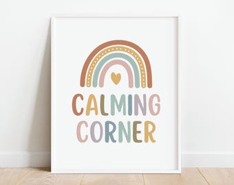 Puede incluir: Una impresión enmarcada en blanco con un arcoíris en tonos marrones, rosas, azules y verdes con un pequeño corazón amarillo en el centro. El texto "CALMING CORNER" está escrito en una fuente colorida debajo del arcoíris.