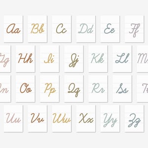 Könnte beinhalten: Ein Satz von 26 Alphabet-Karten mit kursiven Buchstaben in verschiedenen Farben, darunter Rosa, Braun, Gold, Blau und Grau. Jede Karte zeigt einen einzelnen Buchstaben auf weißem Hintergrund mit liniertem Papier.