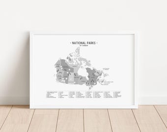 May include: A framed grayscale map of Canada, labeled "National Parks of Canada." The map highlights various national parks with small icons. A list of park names and numbers is at the bottom. The frame is white, and the background is a light wood.