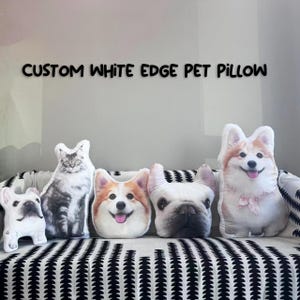 Puede incluir: Cinco almohadas personalizadas para mascotas con bordes blancos. Las almohadas presentan imágenes de un gato, dos corgis y dos bulldogs franceses. Las almohadas están dispuestas en un sofá a rayas blancas y negras.