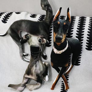 May include: Three plush dog pillows, one grey and white, one black and brown, and one brown and white. The pillows are all in different poses and have realistic facial features.