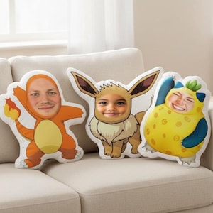 May include: Three custom-made character pillows featuring faces. The pillows are shaped like Pokemon characters: Charmander, Eevee, and a yellow creature. The Charmander pillow is orange with a flame, Eevee is tan and white, and the yellow creature has blue accents.