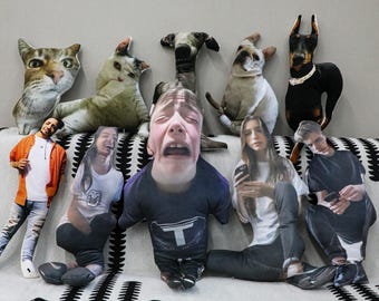 May include: A collection of custom-printed pillows featuring various pets and people. The pillows include images of cats, dogs, and several individuals with different facial expressions. The pillows are arranged on a patterned couch.