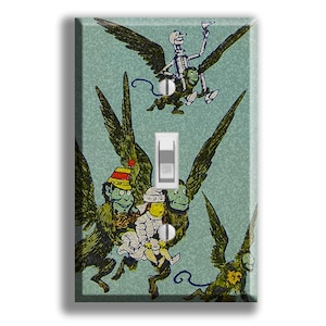 May include: A decorative light switch cover featuring a whimsical illustration of winged monkeys carrying figures. The artwork is in shades of green, yellow, and white, with a light blue background. The switch is white.