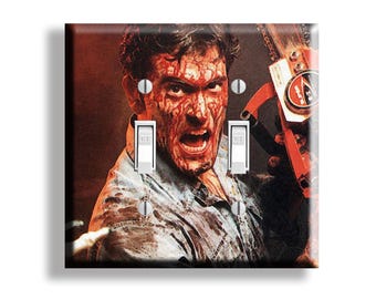 May include: A decorative light switch cover featuring a horror movie scene. The image shows a man covered in blood, with a chainsaw, and the word "OFF" on the switch. The background is dark red.
