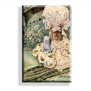 May include: A rectangular light switch plate featuring a vintage-style illustration of a mouse wearing a ruffled bonnet and dress. The mouse is positioned against a green patterned background with another small mouse peeking from behind a cushion.