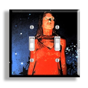 May include: A decorative light switch cover featuring a surreal image of a person in a red dress against a starry blue and black background. The switch is in the "OFF" position.