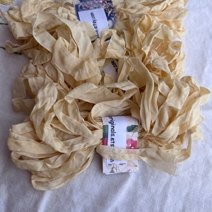 May include: A pile of pale yellow silk ribbon, with a white label that reads "originals.etsy.com".