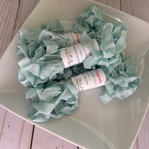 May include: A close-up of a white ceramic bowl filled with light blue crinkled ribbon. The ribbon is labeled "Sky Blue" and "Originals" with the website address "etsy.com".