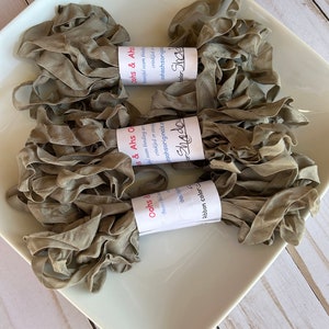 May include: Three spools of light brown crinkled ribbon with labels that read "Oohs & Ahs" and "Shadow".