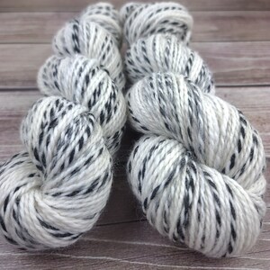 May include: Two skeins of white yarn with black speckles. The yarn is soft and fluffy, and it is perfect for knitting or crocheting.