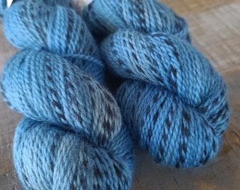 May include: Two skeins of yarn in a blue and black speckled pattern. The yarn is soft and fluffy, and it would be perfect for knitting or crocheting.