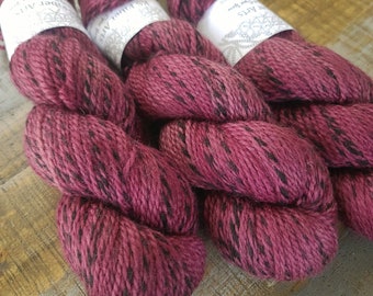 May include: Three skeins of deep red yarn with black flecks. The yarn is labeled "Fiber Arts" and "Twist Wool".