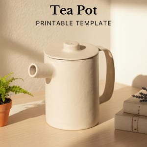 May include: A cream-colored ceramic teapot with a cylindrical body, a rounded lid, and a curved handle. The spout extends horizontally from the body. The text "Tea Pot PRINTABLE TEMPLATE" is printed above the teapot.