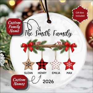 Peut inclure: Une décoration de Noël ronde en céramique blanche avec le texte The Smith Family, une branche brune avec des aiguilles de pin et des nœuds rouges, et quatre étoiles suspendues à motifs flocon, carreaux et pois, avec les noms SUZAN, HENRY, EMILIA, MAX et 2026.