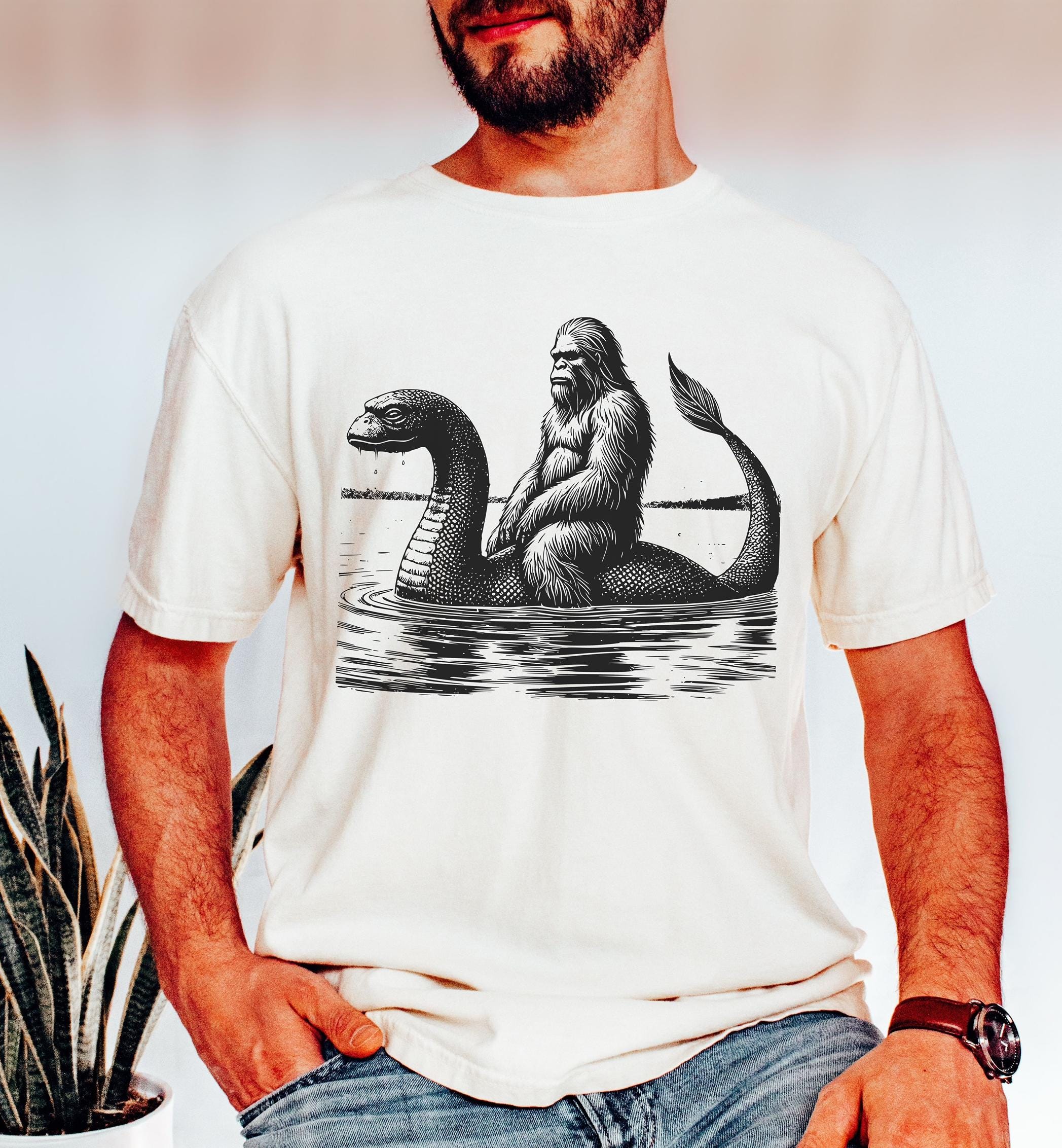 Funny Bigfoot Riding Loch Ness Dinosaur T-Shirt, Sasquatch Tee, Humorous Cryptid Shirt, Novelty Unisex Top, Mythical Creature Gift