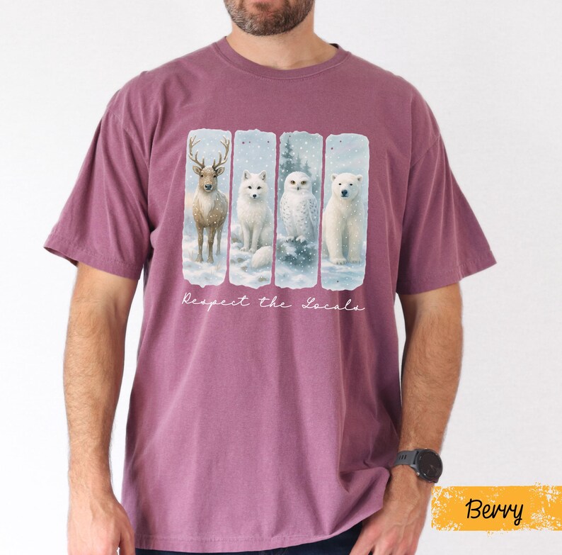 Puede incluir: Camiseta color bayas con un gr&aacute;fico de un ciervo, un zorro, un b&uacute;ho y un oso polar en un paisaje nevado. El texto "Respect the Locals" est&aacute; impreso debajo. La camiseta es de cuello redondo y manga corta.