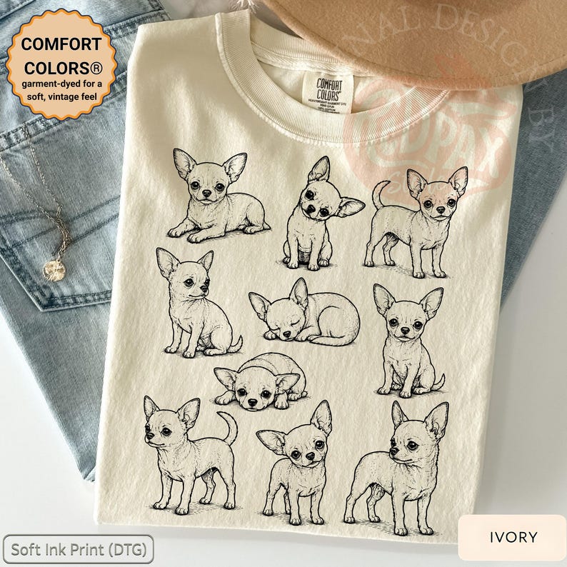 May include: An ivory-colored t-shirt featuring a black line-art graphic of nine different Chihuahua dogs in various poses. The shirt has a Comfort Colors brand label at the neck, and the design includes illustrations of the dogs sitting, standing, and sleeping.