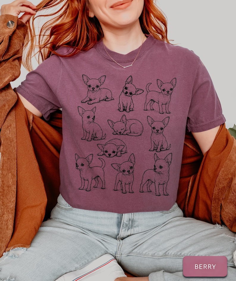 May include: A berry-colored short-sleeve t-shirt featuring a black line-art graphic print of nine different Chihuahua dogs in various poses, including sitting, standing, and lying down. The shirt has a crew neckline and a relaxed fit.
