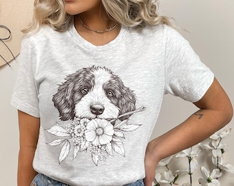 Puede incluir: Una camiseta gris con una ilustración en blanco y negro de la cabeza de un perro con flores en la boca.