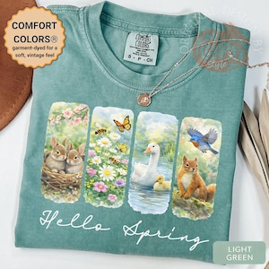 Peut inclure: T-shirt vert clair Comfort Colors avec un motif "Hello Spring". Le motif présente quatre panneaux avec des illustrations de lapins, d'abeilles, d'un canard et d'un écureuil. Le t-shirt a un toucher doux et vintage.
