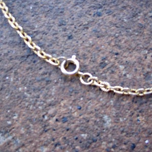 May include: A gold-toned metal chain necklace featuring a circular spring ring clasp mechanism. The chain consists of small, interconnected oval links that form a continuous loop, with the clasp serving as the primary point of connection.