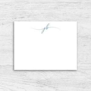 May include: A white card with the initials "jb" written in a cursive script in blue ink.