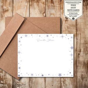 May include: White note cards with a star design border and the name "Samantha Johnson" in a script font. The cards are accompanied by a brown envelope. The label reads "PIXIE DUST NOTE CARDS" and the cards measure 5.5" x 4.25".