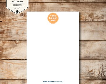 May include: A white notepad with an orange circle that says "YOUR LOGO HERE". The notepad is 5" x 7" and has the text "James Johnson President/CEO" at the bottom. The notepad is labeled "PERSONALIZED ITEM BUSINESS LOGO NOTEPAD 50 SHEETS".