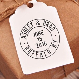 May include: A white gift tag with a black circle stamp that says "Ashley & Brad, June 15, 2016, Buffalo, NY".
