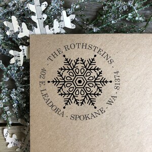 May include: A brown paper envelope with a black snowflake design and the text "THE ROTHSTEINS 402 E. LEADORA - SPOKANE - WA - 81374" printed on it.