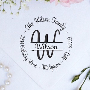 May include: A round, black and white return address stamp with the text "The Wilson Family" and "2234 Codlsey Lane - Medgazan - MD 21717" surrounding a stylized "W" with the name "Wilson" centered below the letter.