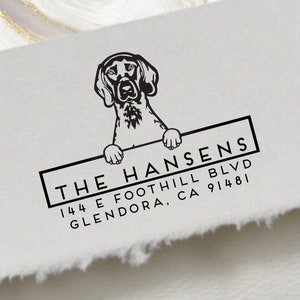 May include: Black and white illustration of a dog holding a sign that reads "THE HANSENS 144 E FOOTHILL BLVD GLENDORA, CA 91481".