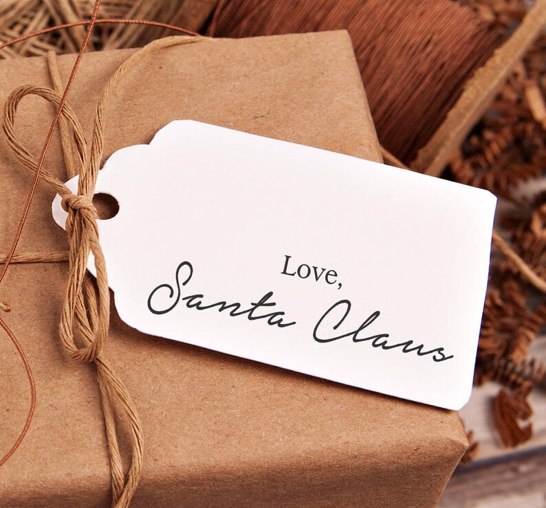 May include: A brown paper gift bag with a white tag tied with twine. The tag has the text "Love, Santa Claus" written in black cursive.