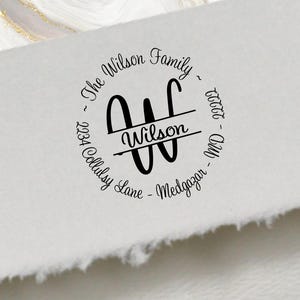 May include: A black custom family address stamp with the text "The Wilson Family" in a circular design. The stamp includes the address "2234 Collinsy Lane - Medgazor - MD - 22222" and a stylized "W" initial.