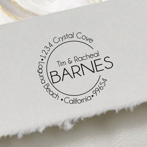 May include: A black and white round return address stamp with the text "•1234 Crystal Cove Laguna Beach • California • 99654" and "Tim & Racheal BARNES" in the center.