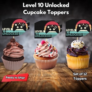May include: Set of 12 cupcake toppers featuring a black and white retro video game controller with the text "Level 10 Unlocked".
