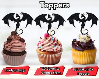 May include: Three cupcakes decorated with black glitter dragon cupcake toppers. The cupcakes are frosted with pink, brown, and white frosting. The text "Dragon Cupcake Toppers" is at the top of the image. The text "Ready to Ship!" is below the left cupcake. The text "10 Colors to Choose From" is below the middle cupcake. The text "Set of 6 or 12+ Toppers" is below the right cupcake.