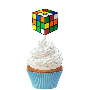 Puede incluir: Un cupcake azul con glaseado blanco y chispas azules coronado con un adorno de pastel en forma de cubo de Rubik de colores.