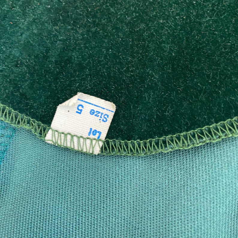 Puede incluir: Primer plano de una tela de terciopelo verde con una etiqueta blanca que dice "Talla S" y "Lote 101".