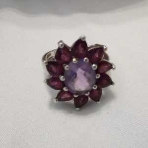 925 Silver, with 2.50 ct center Amethyst and 10 Rhodolite petals totaling 3.50 ct. Size 7. This style making a resurgence on JTV for 135