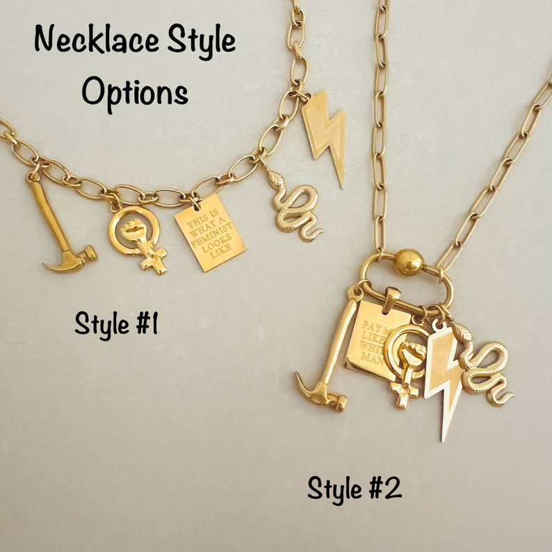 May include: Two gold necklaces with different charms. The first necklace has a hammer, a feminist symbol, and a small sign that says "This is what a feminist looks like". The second necklace has a hammer, a feminist symbol, a lightning bolt, a snake, and a sign that says "Pay me like a white man".