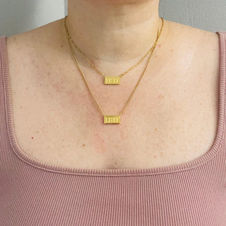 May include: Two gold necklaces with rectangular pendants that read "11:11".