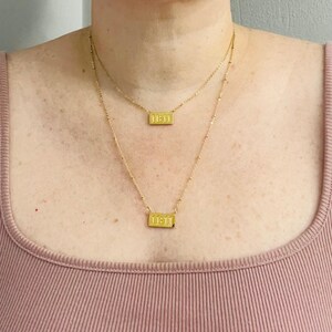 May include: Two gold necklaces with rectangular pendants that read "11:11".