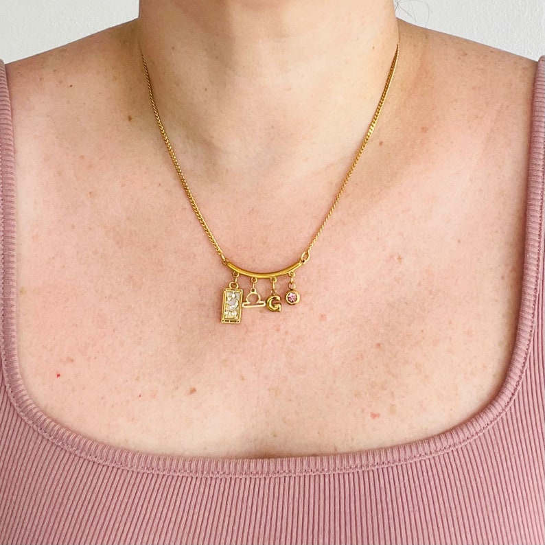 Peut inclure: Collier en or avec un pendentif zodiaque Balance, un petit pendentif lettre 'G' et un pendentif en cristal rose.