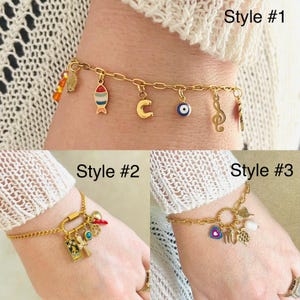May include: Three gold charm bracelets with different charms. The first bracelet has a fish, a letter C, an evil eye, and a music note charm. The second bracelet has a padlock, a red chili pepper, a green gem, and a small book charm. The third bracelet has a circle charm, a heart, a turtle, and a pearl charm.