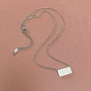 May include: A silver chain necklace with a silver pendant that says "11:11" on it.