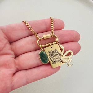 以下が含まれることがあります： ゴールドチェーンネックレス。ゴールドチャームにはメデューサの頭のデザイン、グリーンストーン、ゴールドのスネークチャームが施されています。