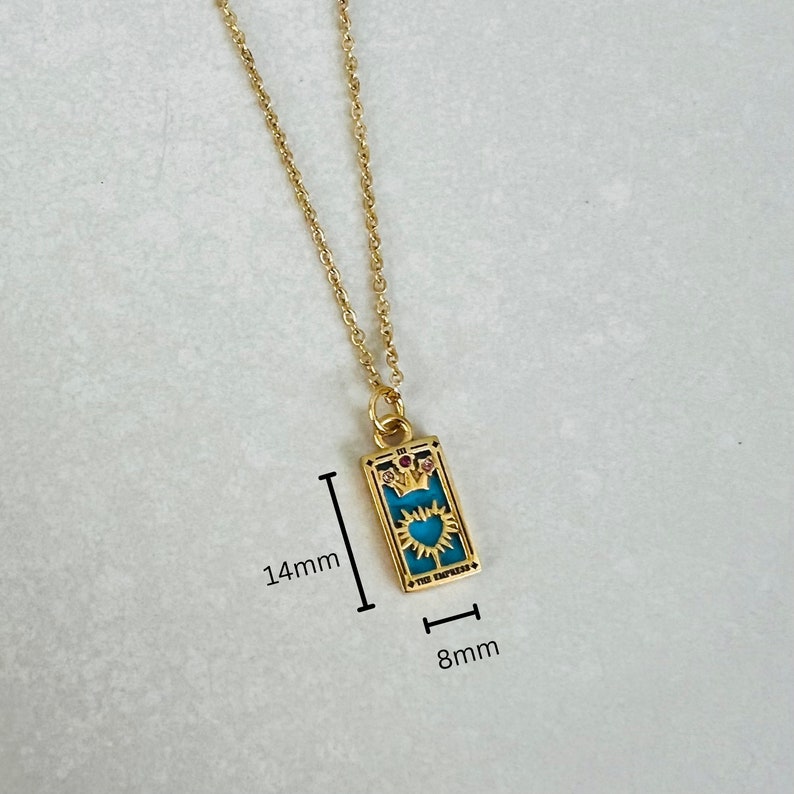 Peut inclure: Collier en or avec un pendentif bleu turquoise repr&eacute;sentant un design de carte de tarot. La carte repr&eacute;sente l'Imp&eacute;ratrice avec une couronne et un c&oelig;ur. Le pendentif mesure 3,5 cm sur 2 cm.